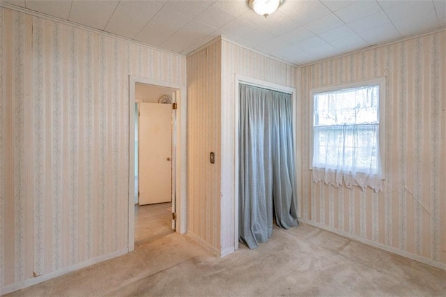 unfurnished bedroom featuring wallpapered walls, carpet, a closet, and baseboards