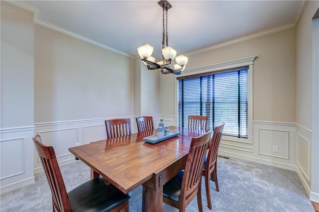 dining room featuring light carpet, a chandelier, crown molding, wainscoting, and a decorative wall