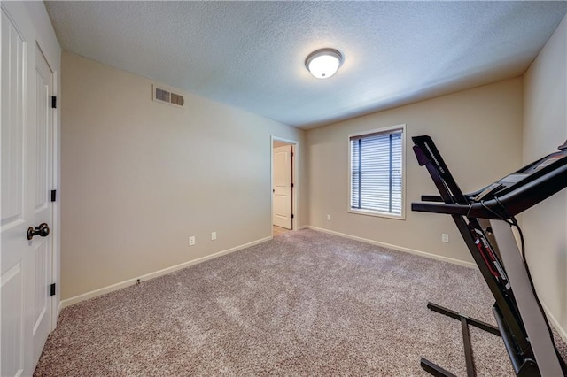 exercise room featuring a textured ceiling, baseboards, and carpet flooring