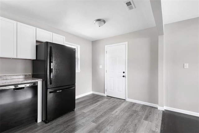 1758 Main St, Osawatomie, KS 66064 - kitchen with white cabinets, dark wood finished floors, baseboards, visible vents, and black appliances