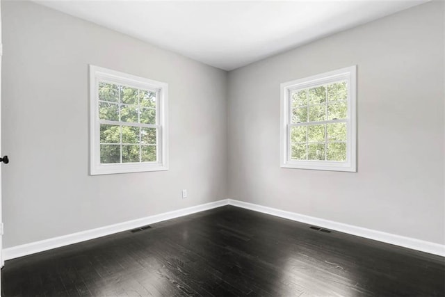 1758 Main St, Osawatomie, KS 66064 - spare room with a healthy amount of sunlight, baseboards, dark wood-style floors, and visible vents
