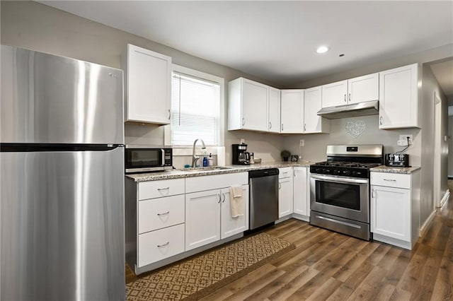 kitchen with a sink, white cabinets, under cabinet range hood, and appliances with stainless steel finishes
