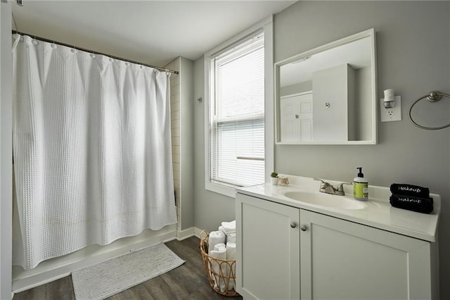 bathroom with vanity, baseboards, shower / bath combo, and wood finished floors