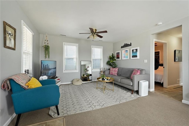 carpeted living room with visible vents, baseboards, and ceiling fan