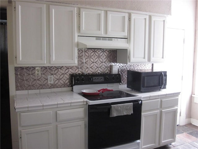 1202 N 8th St, Saint Joseph, MO 64501 - kitchen with electric range, black microwave, under cabinet range hood, white cabinets, and decorative backsplash