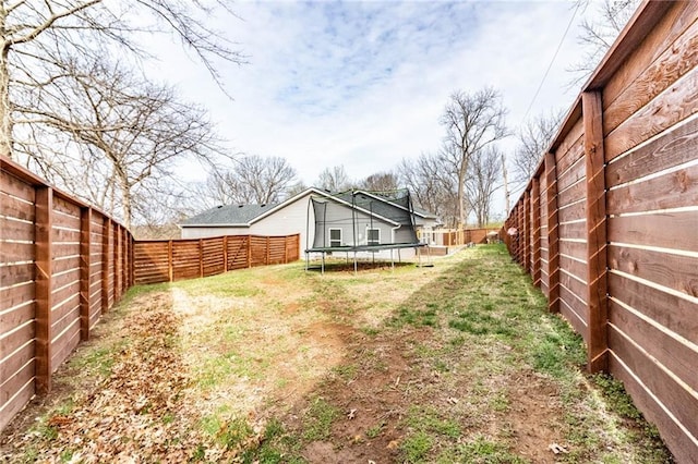 view of yard featuring a trampoline and a fenced backyard