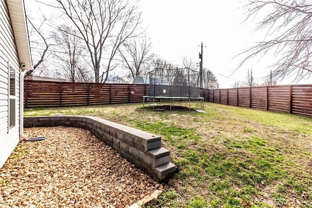 view of yard featuring a trampoline and a fenced backyard