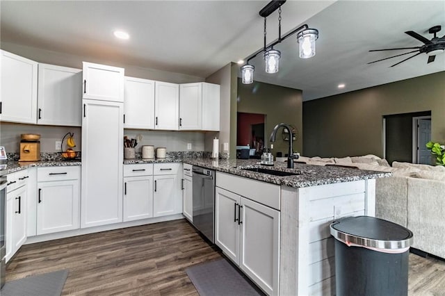 kitchen featuring a sink, a peninsula, stainless steel dishwasher, open floor plan, and dark stone counters