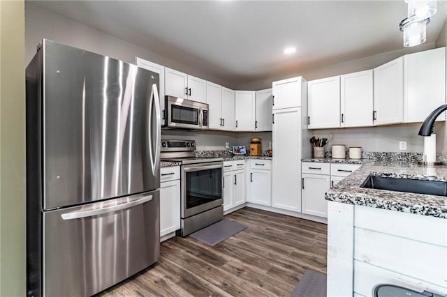 kitchen with dark wood-style flooring, a sink, stainless steel appliances, and light stone counters