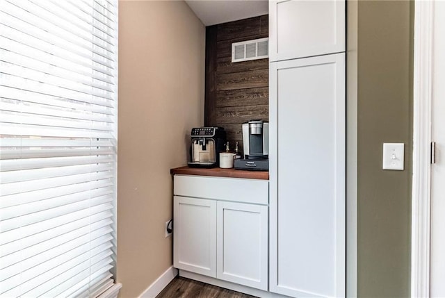 kitchen featuring wood walls, butcher block counters, visible vents, white cabinets, and dark wood-type flooring