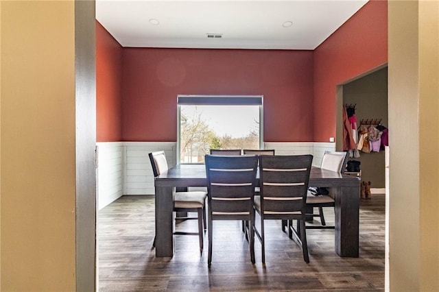 dining space featuring wood finished floors, visible vents, and wainscoting