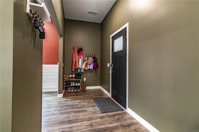 foyer with baseboards, visible vents, and wood finished floors