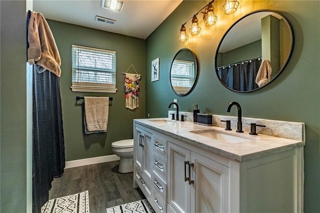 full bath with visible vents, a sink, toilet, and wood finished floors