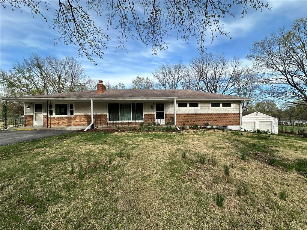 single story home with a chimney, a front yard, brick siding, and aphalt driveway