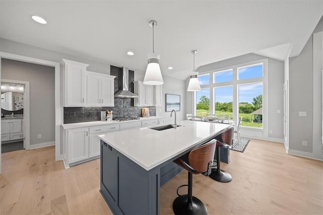 4275 Lake Shore Ct, Basehor, KS 66007 - kitchen with wall chimney exhaust hood, a sink, white cabinetry, baseboards, and stainless steel gas stovetop