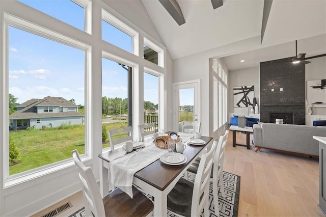4275 Lake Shore Ct, Basehor, KS 66007 - dining space featuring healthy amount of natural light, light wood-style flooring, ceiling fan, a tiled fireplace, and high vaulted ceiling