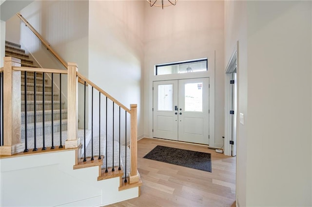 907 Reed Dr, Raymore, MO 64083 - foyer entrance featuring wood finished floors, a towering ceiling, stairs, and a chandelier