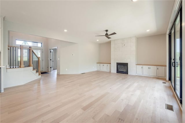 907 Reed Dr, Raymore, MO 64083 - unfurnished living room featuring healthy amount of natural light, light wood-type flooring, ceiling fan, recessed lighting, and a tile fireplace