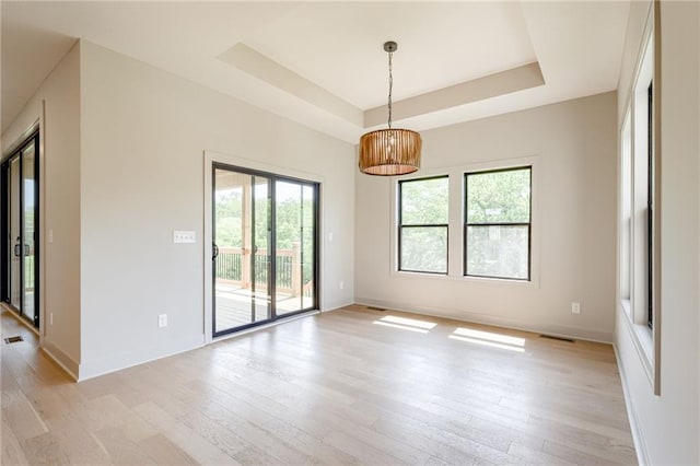 907 Reed Dr, Raymore, MO 64083 - spare room featuring a raised ceiling and light wood-style floors