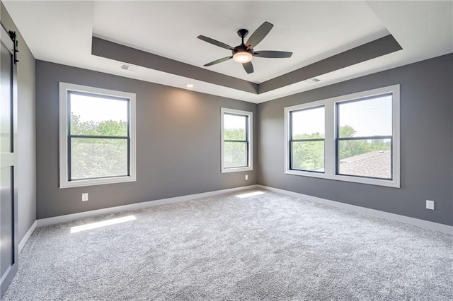 907 Reed Dr, Raymore, MO 64083 - carpeted spare room with a tray ceiling, ceiling fan, and a barn door