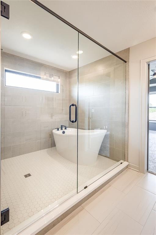 907 Reed Dr, Raymore, MO 64083 - bathroom featuring a shower stall, plenty of natural light, and a soaking tub