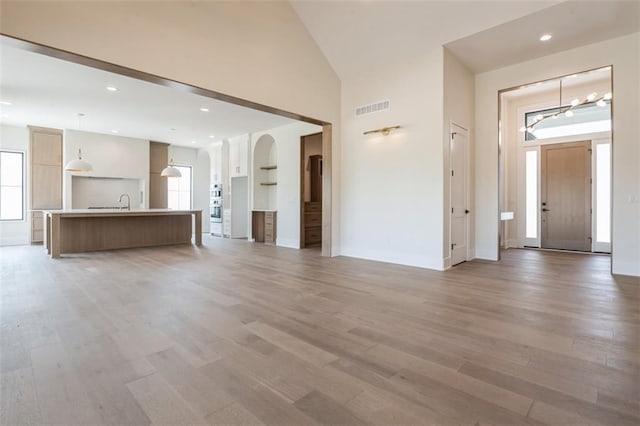 17041 Earnshaw St, Overland Park, KS 66221 - unfurnished living room featuring light wood-style flooring, a chandelier, high vaulted ceiling, and recessed lighting
