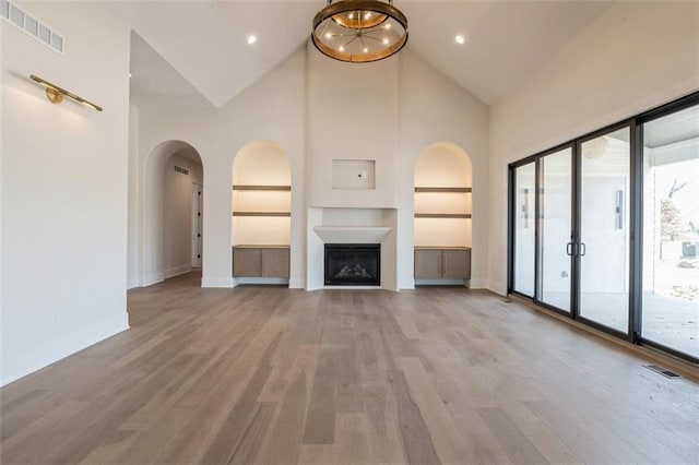 17041 Earnshaw St, Overland Park, KS 66221 - unfurnished living room featuring high vaulted ceiling, light wood finished floors, arched walkways, and a fireplace