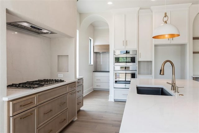 17041 Earnshaw St, Overland Park, KS 66221 - kitchen with appliances with stainless steel finishes, light wood-type flooring, white cabinetry, light stone countertops, and pendant lighting