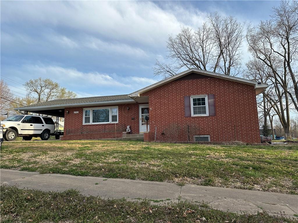 ranch-style house featuring a carport, a front yard, and brick siding