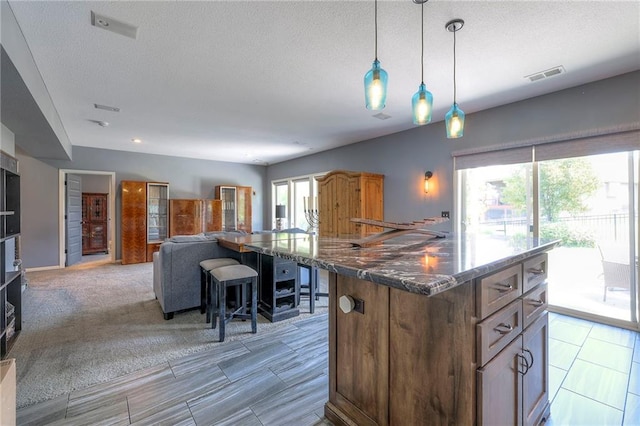 11237 S Race St, Olathe, KS 66061 - kitchen featuring open floor plan, decorative light fixtures, dark stone counters, a textured ceiling, and a center island