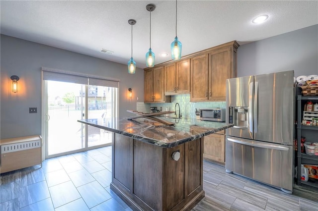 11237 S Race St, Olathe, KS 66061 - kitchen featuring stainless steel appliances, decorative backsplash, dark stone counters, brown cabinetry, and hanging light fixtures