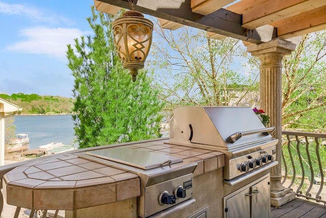 view of patio / terrace with grilling area, a water view, and an outdoor kitchen