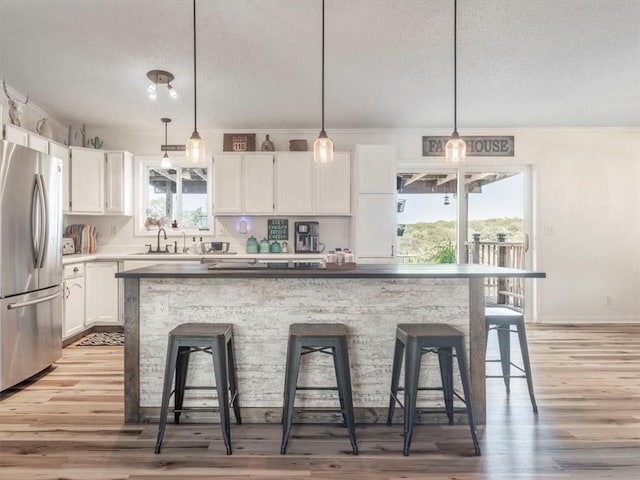 14199 County Road 191, Savannah, MO 64485 - kitchen featuring freestanding refrigerator, white cabinets, a breakfast bar area, and a textured ceiling