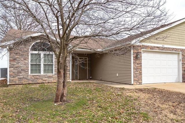 single story home with driveway, stone siding, an attached garage, a front yard, and central AC unit