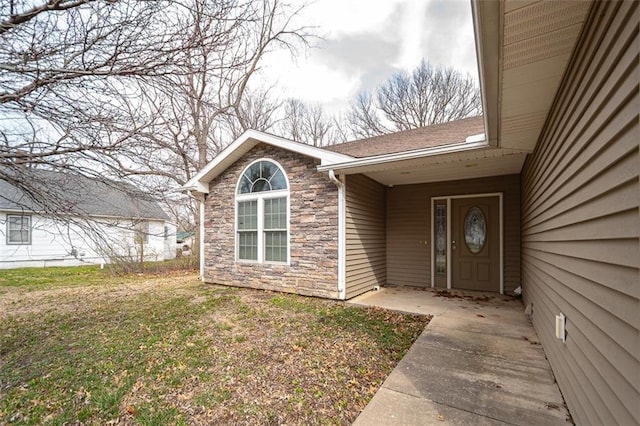 property entrance with stone siding and a yard