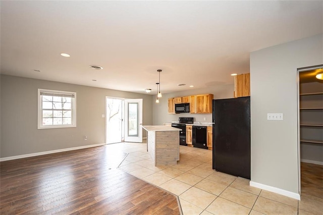 kitchen with black appliances, light countertops, baseboards, and a kitchen island