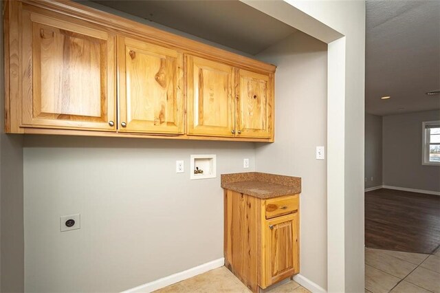 clothes washing area with hookup for a washing machine, light tile patterned floors, baseboards, cabinet space, and electric dryer hookup