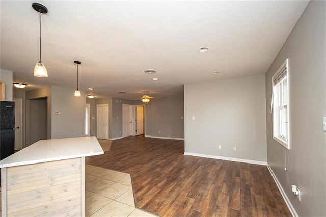 kitchen with baseboards, ceiling fan, light countertops, wood finished floors, and hanging light fixtures
