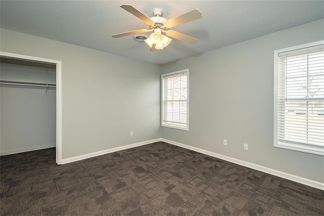 unfurnished bedroom with a closet, dark carpet, a ceiling fan, and baseboards