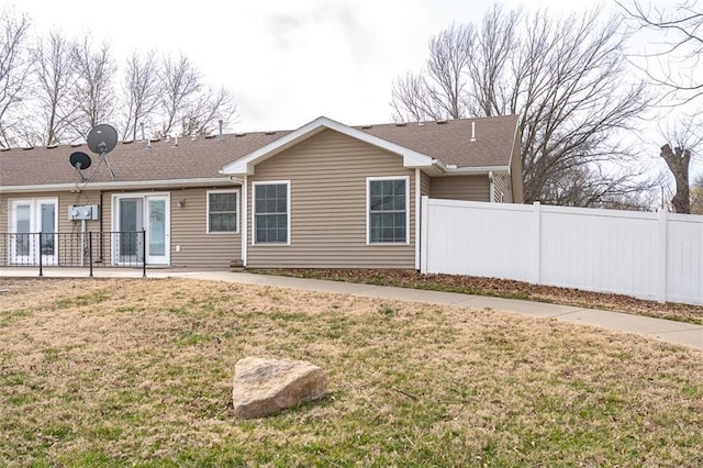 rear view of house featuring a patio, a lawn, and fence