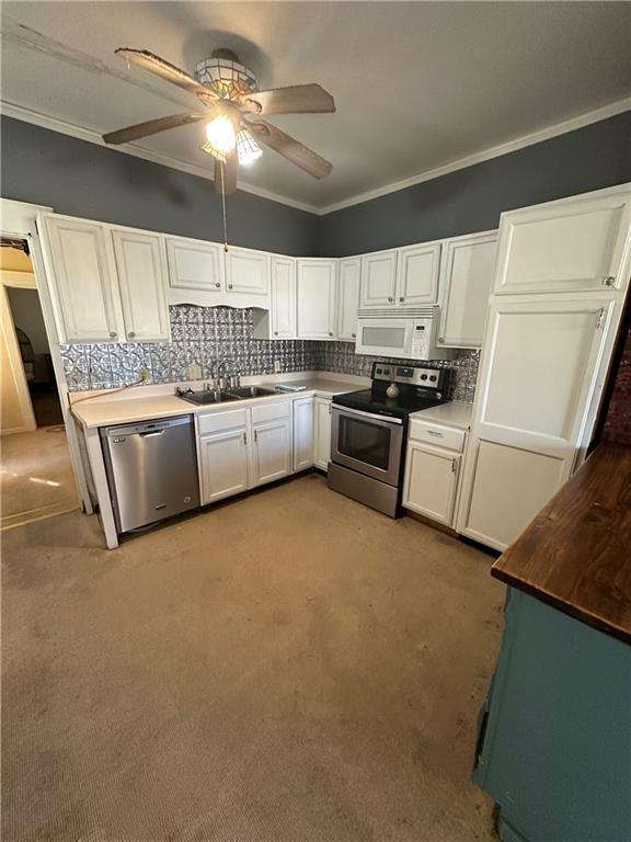 236 N Liberty St, Troy, KS 66087 - kitchen featuring backsplash, stainless steel appliances, white cabinets, crown molding, and ceiling fan