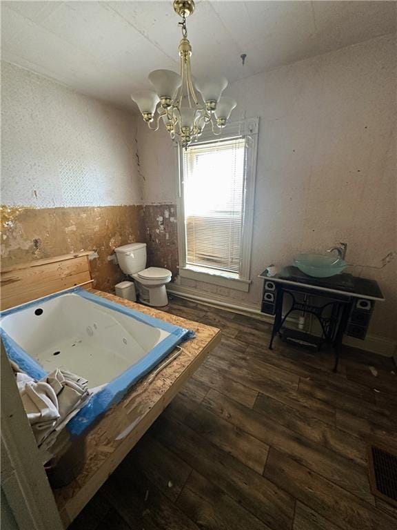 236 N Liberty St, Troy, KS 66087 - interior space with visible vents, a notable chandelier, toilet, a jetted tub, and wood finished floors