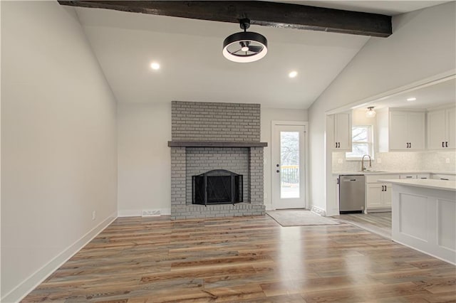 14401 67th St, Parkville, MO 64152 - unfurnished living room with light wood finished floors, a fireplace, vaulted ceiling with beams, and baseboards
