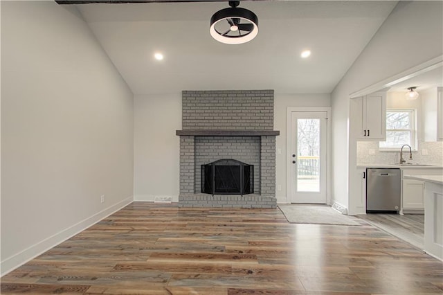 14401 67th St, Parkville, MO 64152 - unfurnished living room with a sink, lofted ceiling, light wood-style floors, and a brick fireplace