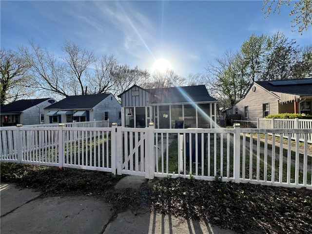 back of property featuring a residential view, board and batten siding, a sunroom, and a fenced front yard