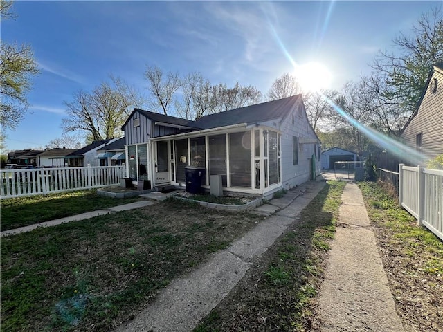 view of front of house with a fenced backyard, a front lawn, and a sunroom