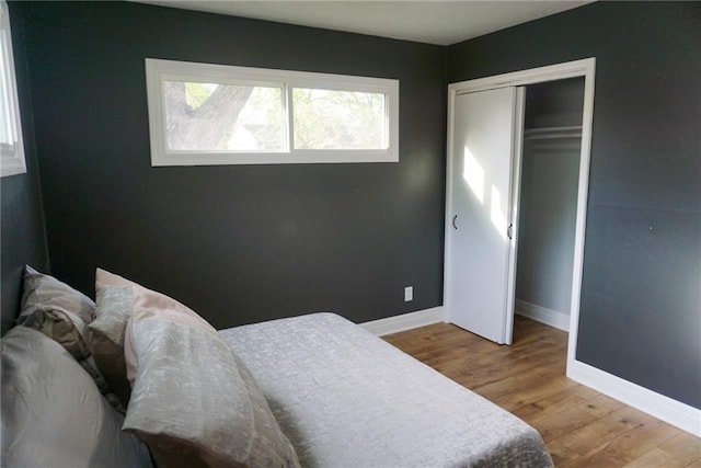 bedroom featuring baseboards, light wood finished floors, and a closet