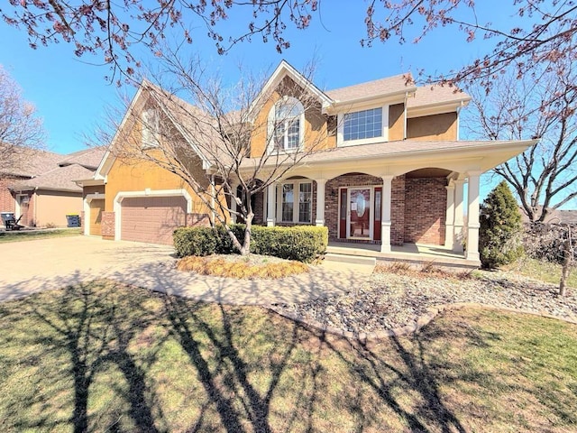 view of front facade with a garage, a porch, driveway, and stucco siding