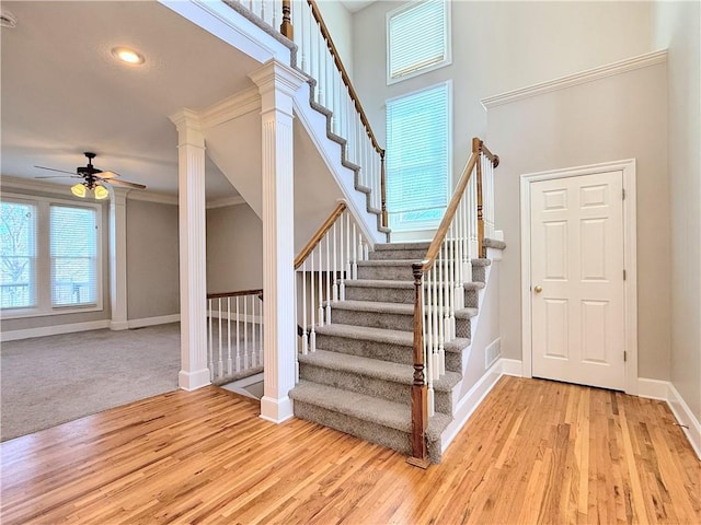 stairs featuring a towering ceiling, baseboards, wood finished floors, and a ceiling fan