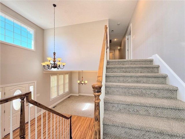 staircase featuring a notable chandelier, wood finished floors, and baseboards